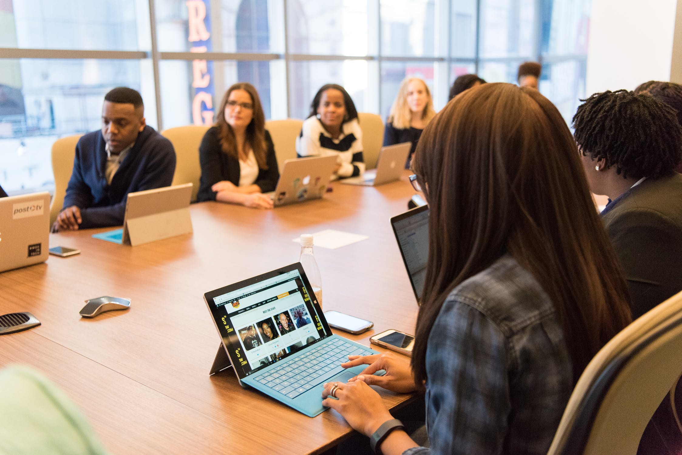 Group of people sitting around a conference table with laptops