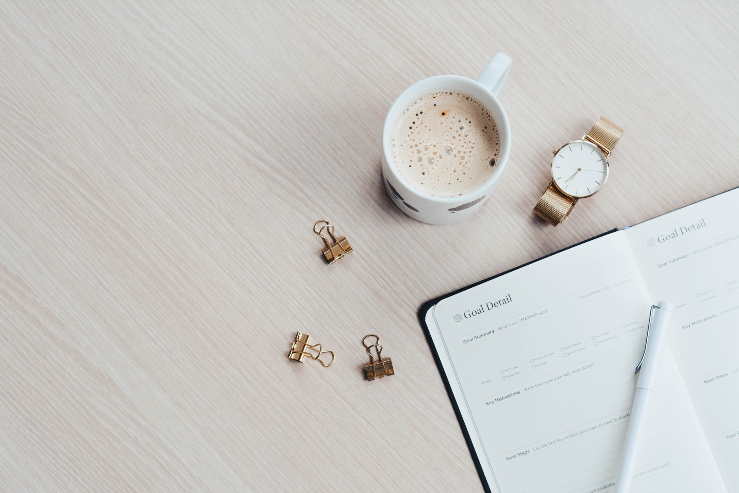 notebook, coffee cup, and watch on a table