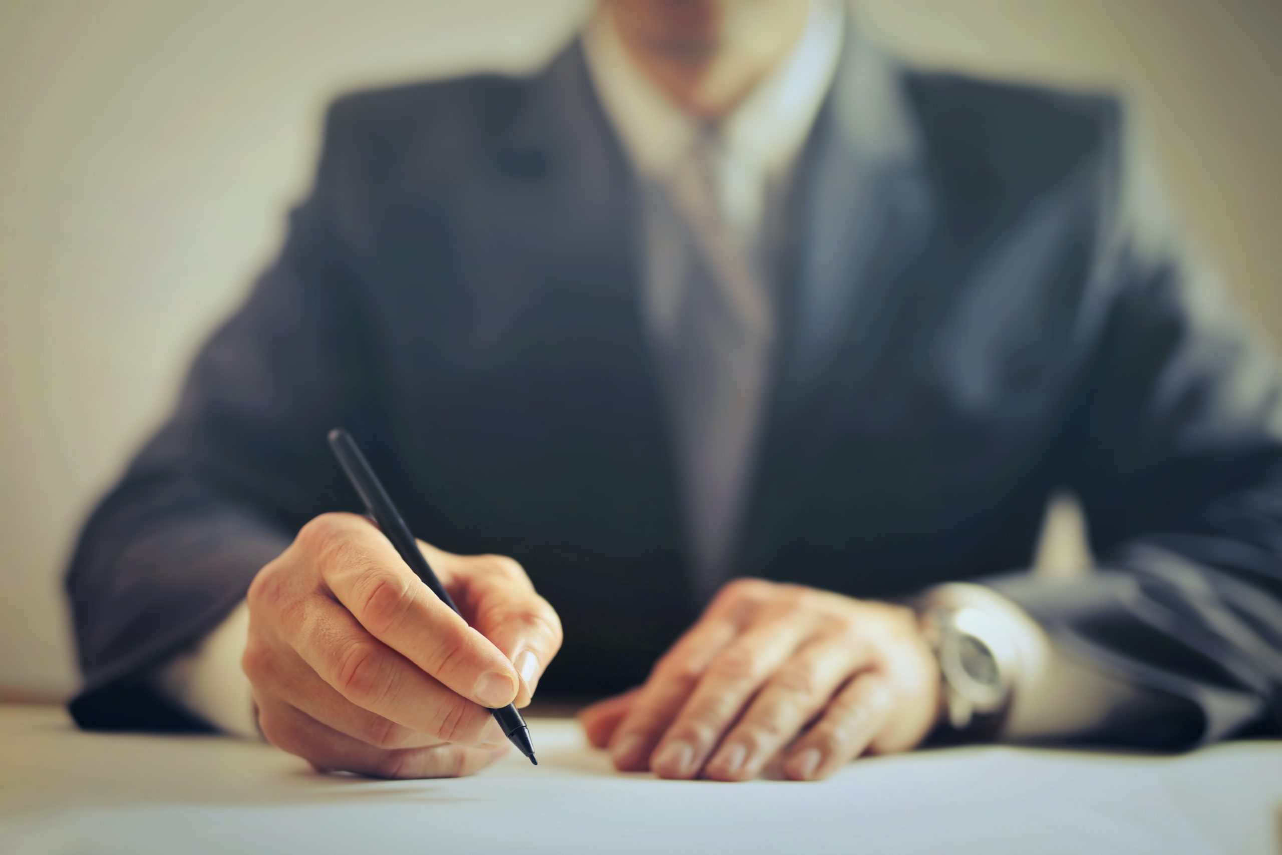 person in a suit signing a document