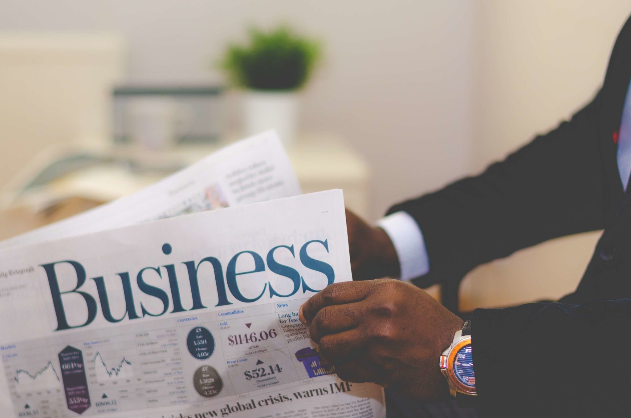 hands holding a newspaper with the headline "Business"