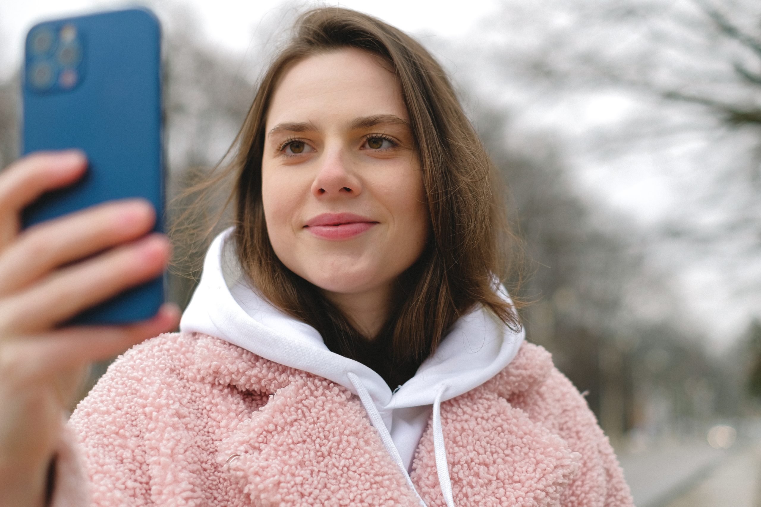 Mulher em um capuz segurando um telefone inteligente