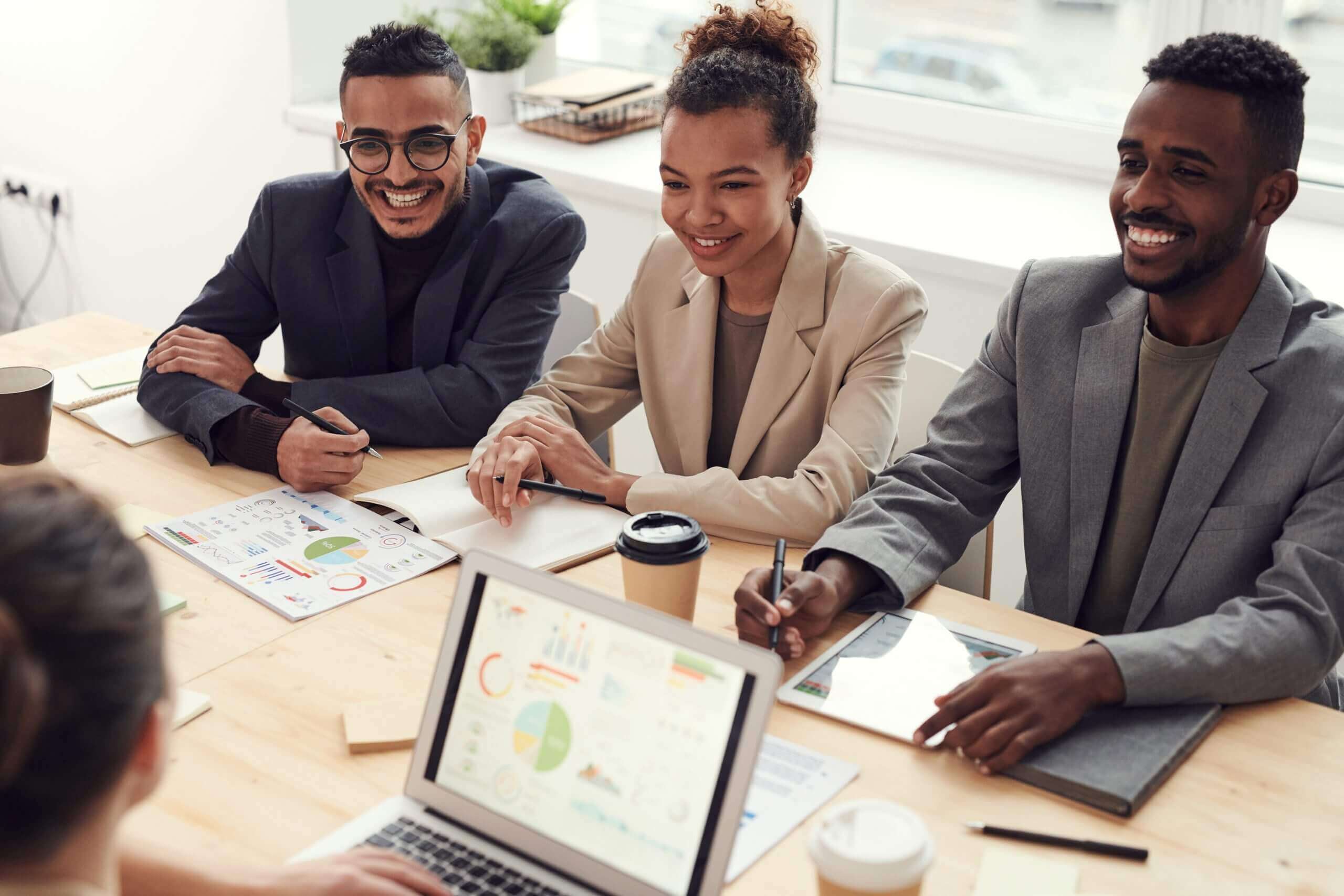 group of businesspeople at a table with laptops and coffee cups